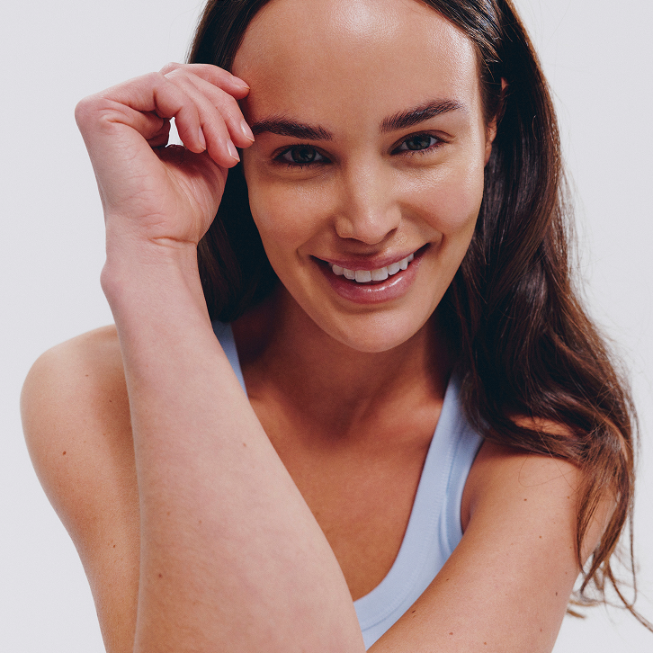 Smiling woman in light blue tank top, natural beauty, healthy skin, minimalist style
